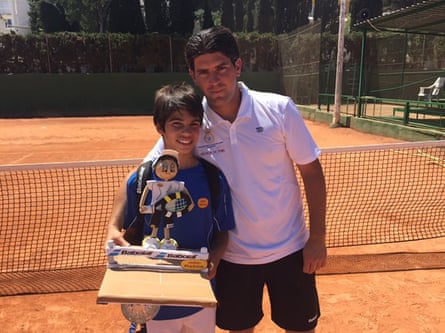 Alcarz and Navarro posing on a clay tennis court with a tennis figurine