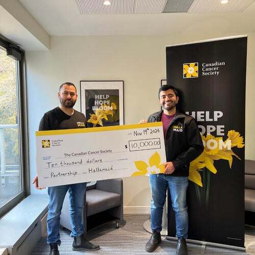 Two individuals hold up large ceremonial cheque