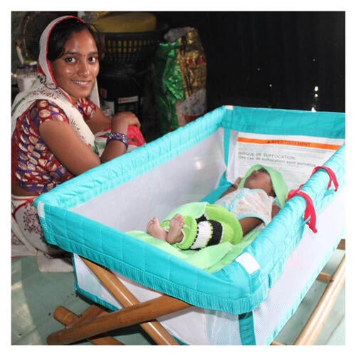 Woman sits beside baby in a crib